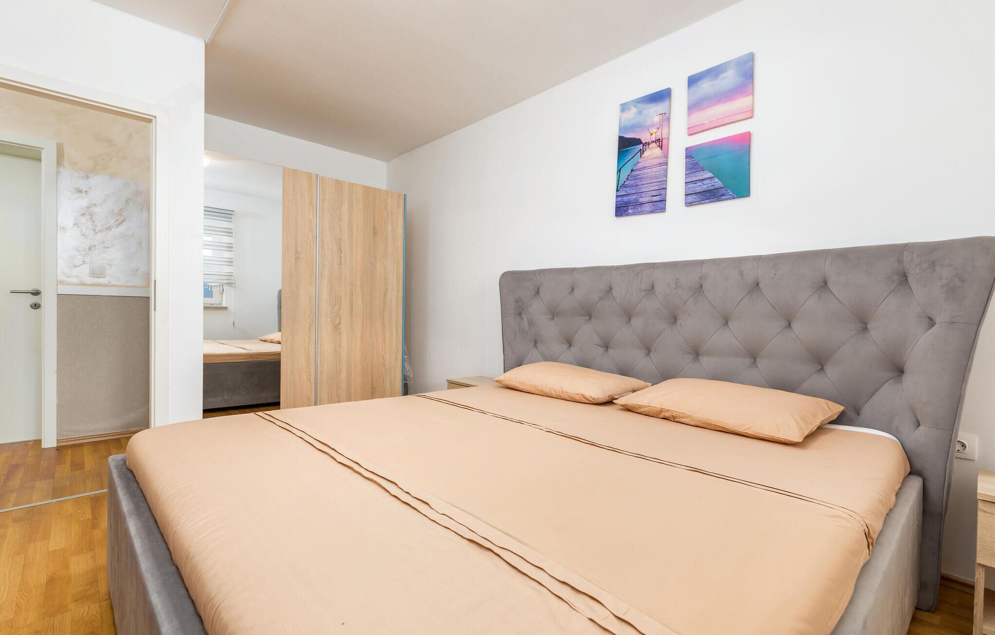 A bedroom with a large bed, a wooden wardrobe, and a desk.