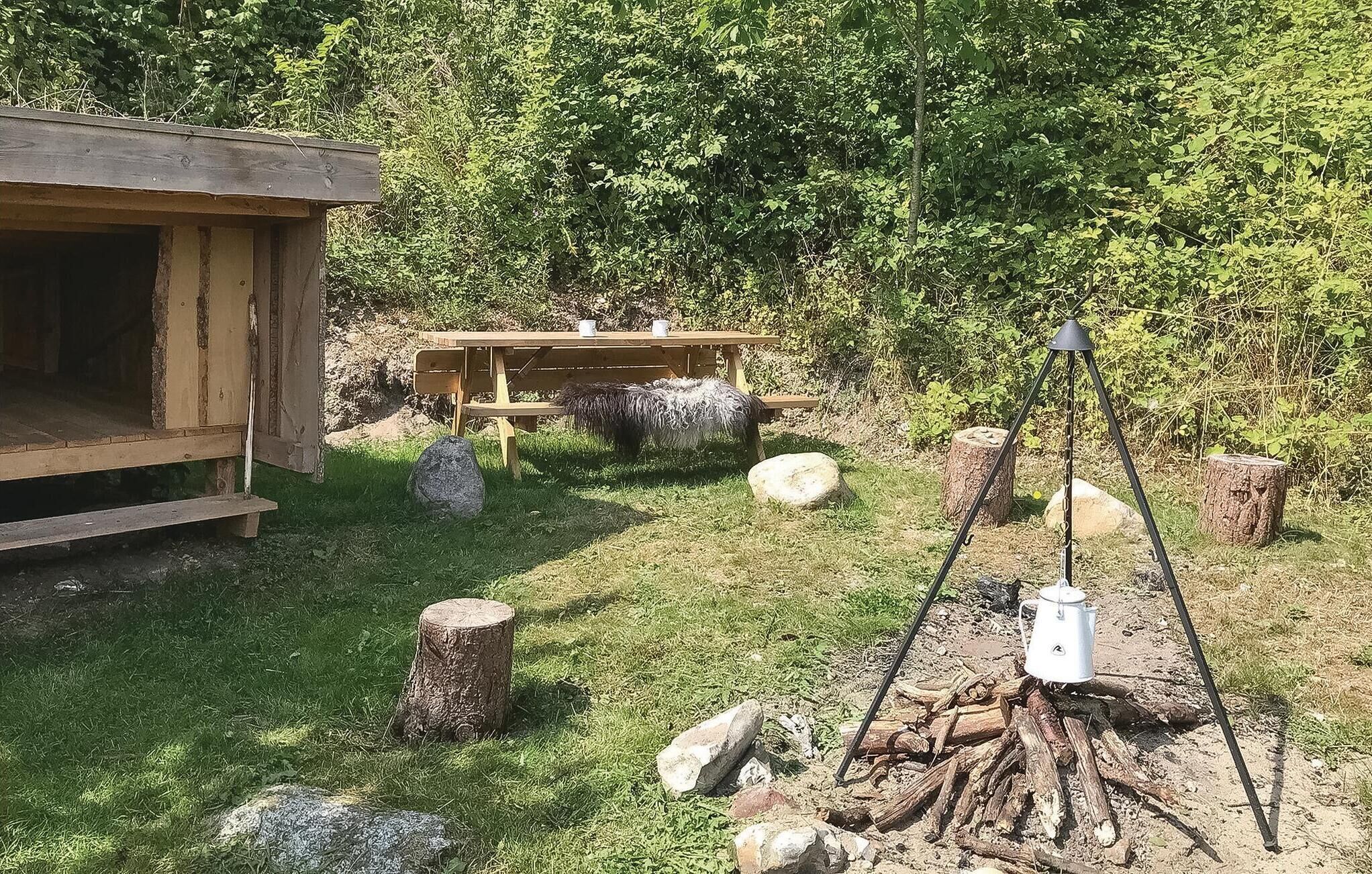 A rustic wooden cabin with a picnic table and a tripod-mounted lantern.