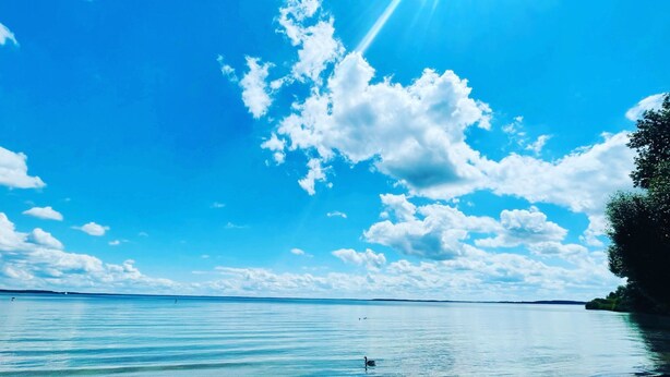 Un lac paisible, avec un ciel dégagé et quelques nuages.