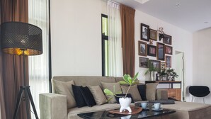 A modern living room with a sofa, a coffee table, and a lamp. - Nan Garden House (Nan)