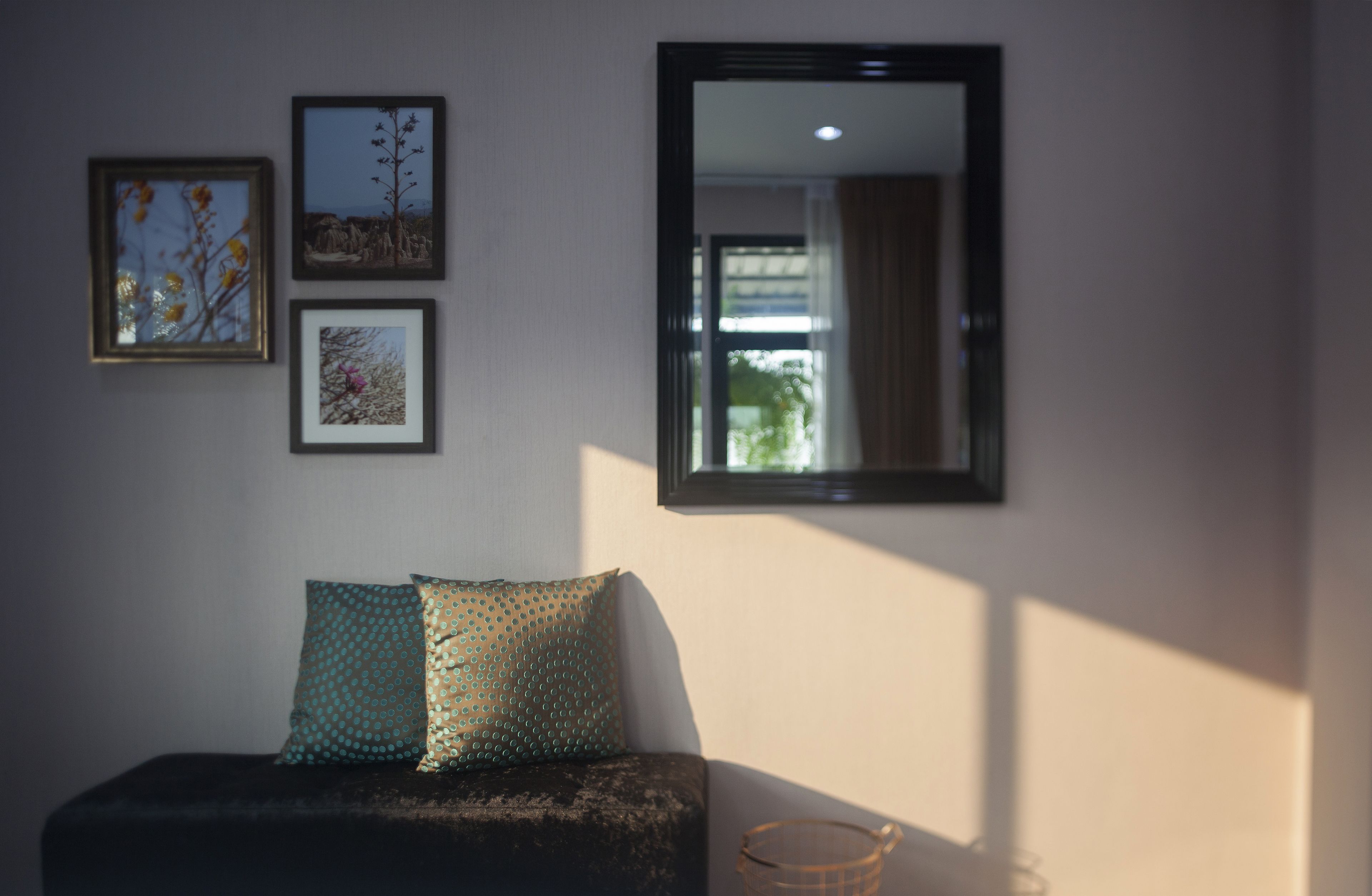 Ein Zimmer mit einer Couch, zwei gerahmten Bildern und einem Spiegel an der Wand.