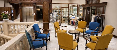 A lobby with marble flooring, wooden furniture, and a view of the store in the background.