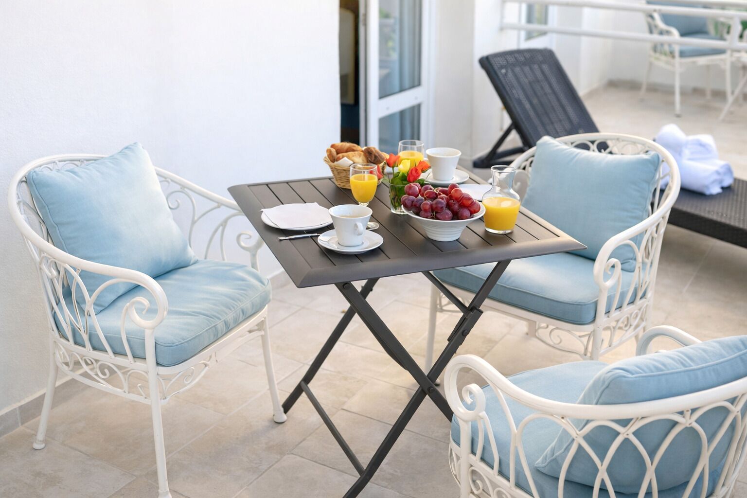 A dining area with a table set for breakfast, including croissants, fruit, and orange juice.