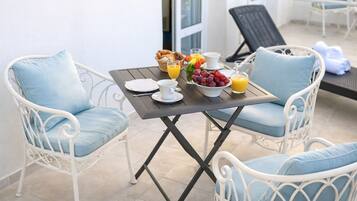 A dining area with a table set for breakfast, including croissants, fruit, and orange juice.
