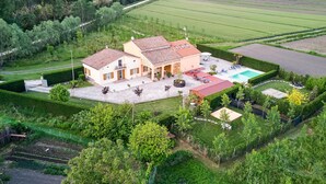 Una casa grande con piscina, rodeada de céspedes y jardines bien cuidados.