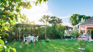 Un patio trasero bien cuidado con una pérgola, mobiliario exterior y un aro de baloncesto.