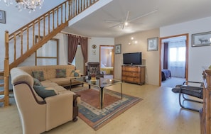 Cozy living space with a high ceiling, comfortable sofa, and wooden staircase.