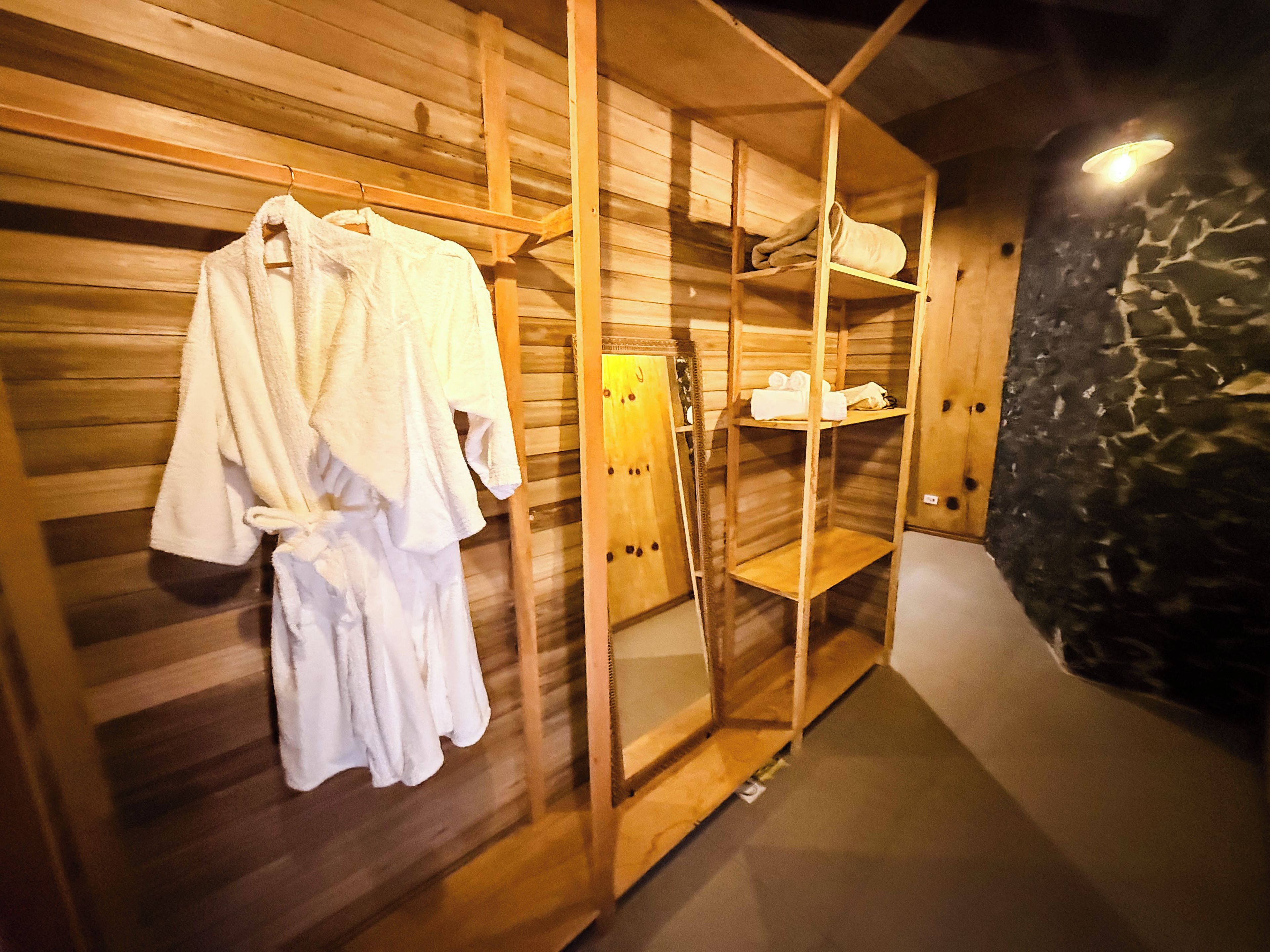 A wooden sauna room with a wooden bench, a towel rack, and a shelf with towels.
