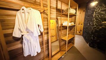 Un sauna en bois, avec un banc en bois, un porte-serviettes et une étagère contenant des serviettes.