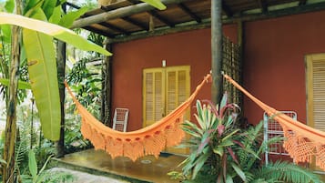 Una hamaca en un entorno tropical con una estructura de madera y abundante follaje.