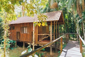 Une cabane en bois avec un toit recouvert de tuiles, entourée d’une végétation luxuriante.