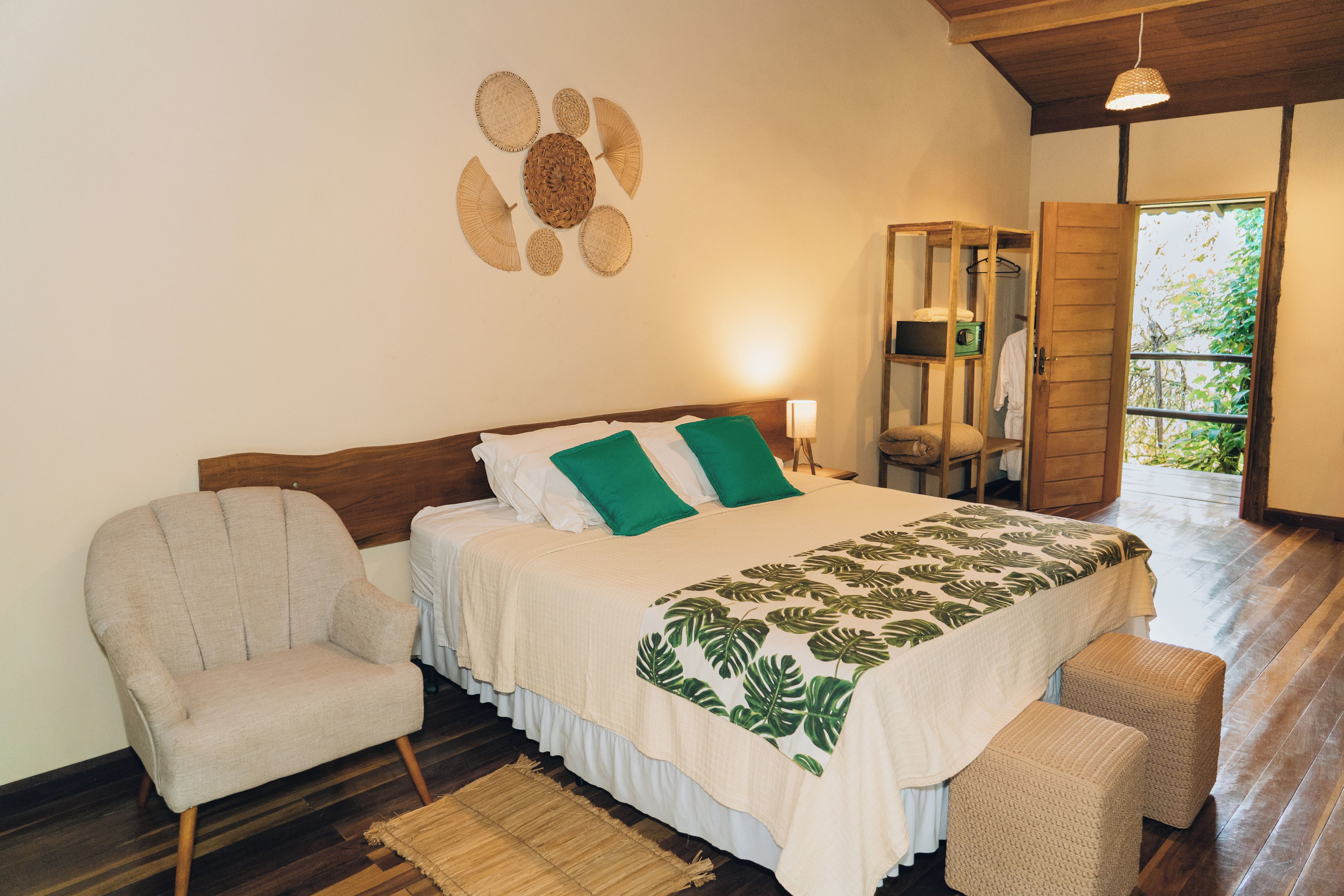 Une chambre à coucher comprenant un lit, une chaise, un banc, un luminaire suspendu et une fenêtre donnant sur un paysage verdoyant.