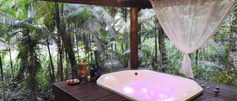 Tinaco en un entorno tropical con una terraza de madera y una pérgola.