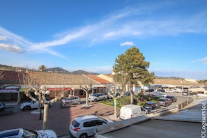 A parking lot with several cars, a few trees, and buildings with signage in the background. - Duplex flat 4/6 persons Port Grimaud (PORT GRIMAUD)