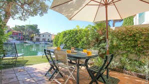 Un patio al aire libre con una mesa, sillas y una sombrilla, con una piscina al fondo.
