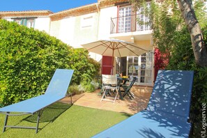 A patio with two lounge chairs, a table, and an umbrella. - Close to the beach house 5/6 persons with mooring and air conditioning (PORT GRIMAUD)