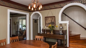 A dining area with a wooden table and chairs, a chandelier, and a vase with flowers.