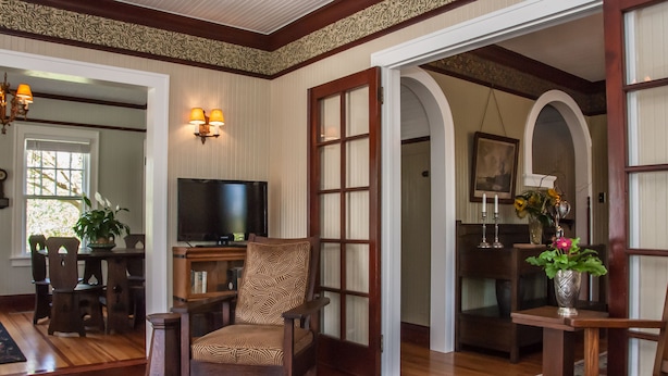 A traditional living room with a television, wooden furniture, and a patterned rug.