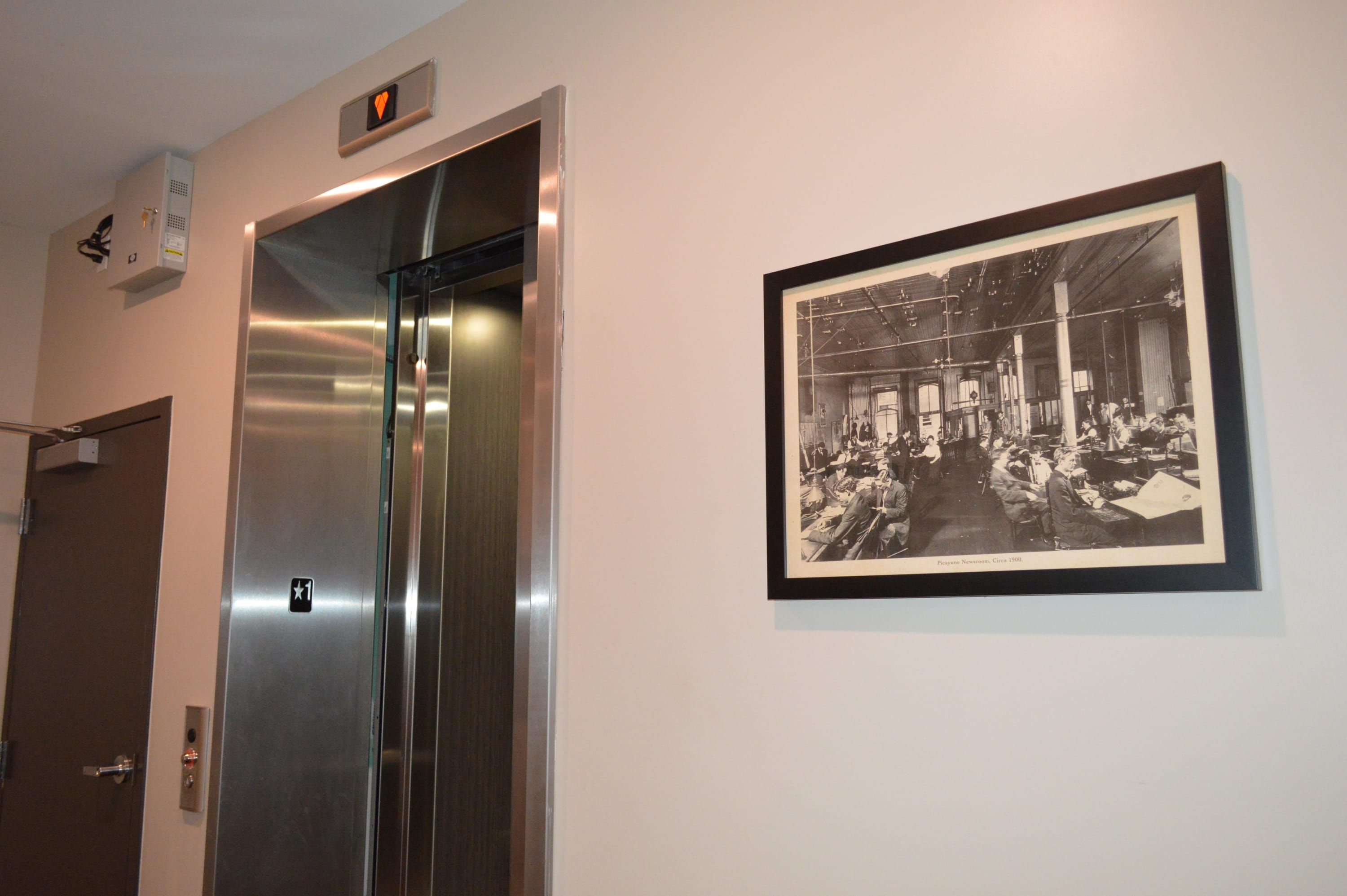 Un ascenseur doté d’un panneau de commande et d’une photographie historique encadrée accrochée au mur.