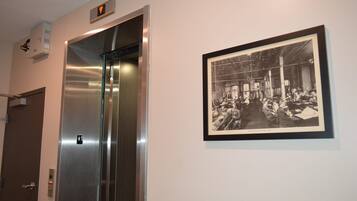 Un ascenseur doté d’un panneau de commande et d’une photographie historique encadrée accrochée au mur.