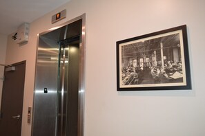 An elevator with a control panel and a framed historical photograph on the wall. - Comics themed, Historic luxury condo, 2 blocks from French Quarter (New Orleans)