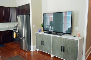 A modern kitchen with a stainless steel refrigerator, a flat-screen TV on a cabinet, and a coffee maker. - Comics themed, Historic luxury condo, 2 blocks from French Quarter (New Orleans)