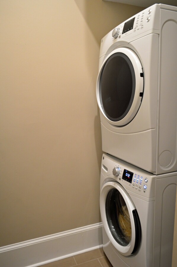 Full size front loading washer and stacked dryer in laundry room