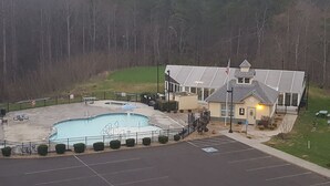 A building with a swimming pool, a parking lot, and a fenced area with benches. - Condo located in the heart of Pigeon Forge, TN   3603 Plaza Drive (Pigeon Forge)