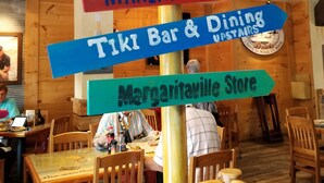 A wooden signpost with multiple directional signs pointing to various locations within a restaurant, including 'Marina Dining' and 'Tiki Bar & Dining Upstairs'. - Condo located in the heart of Pigeon Forge, TN   3603 Plaza Drive (Pigeon Forge)