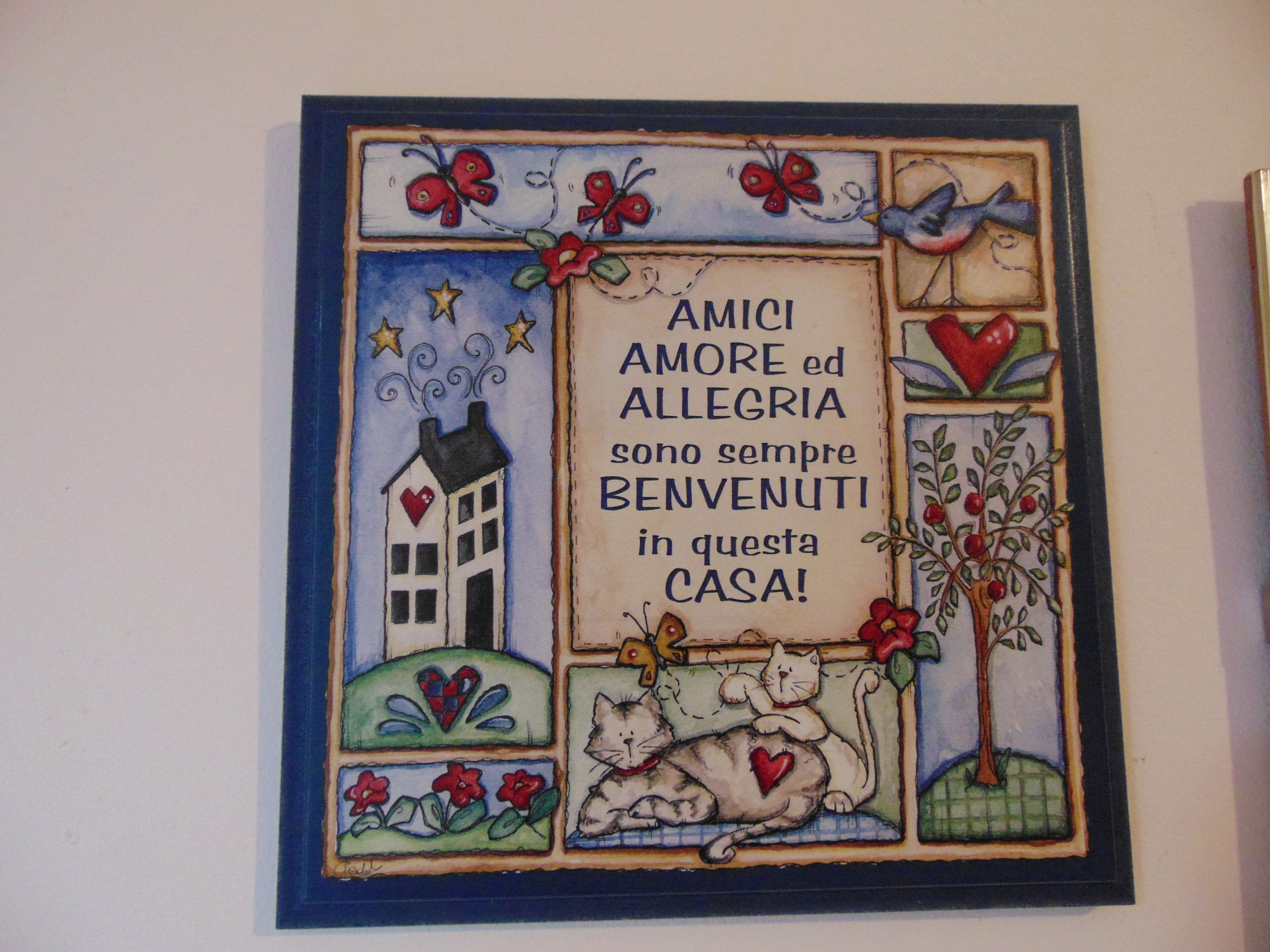 Una ilustración colorida con una casa, mariposas, un gato y un árbol, rodeada de texto en italiano.