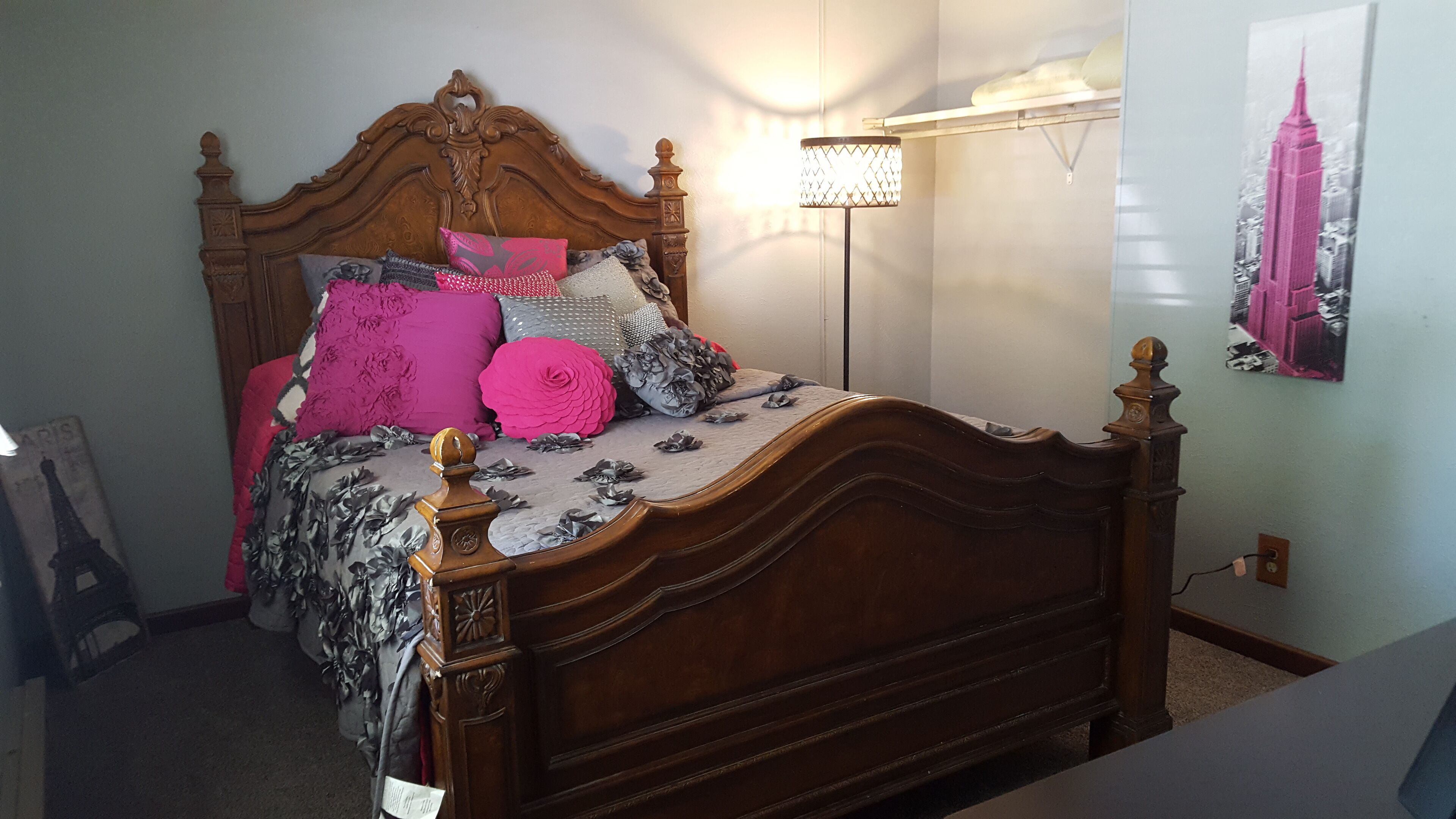 A bedroom with a wooden bed, floral bedding, and a lamp.