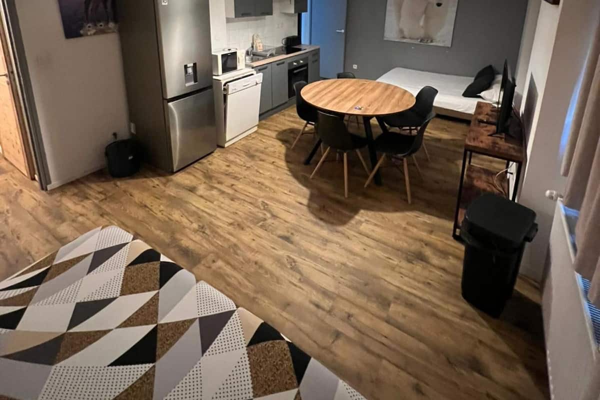 A compact living space with a kitchenette, a dining area with a round table, and a bed.