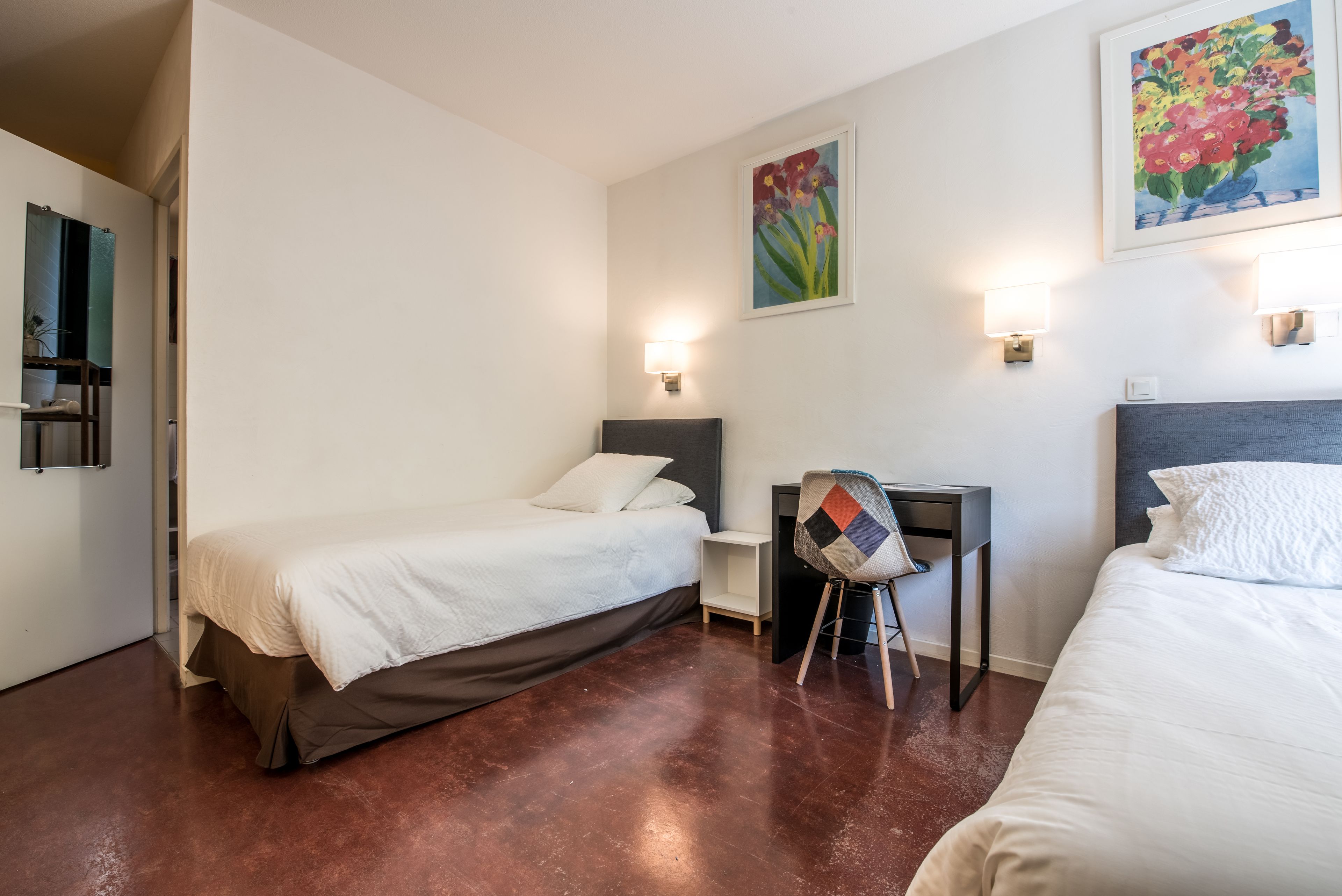Habitación de hotel con dos camas, un escritorio y una silla.