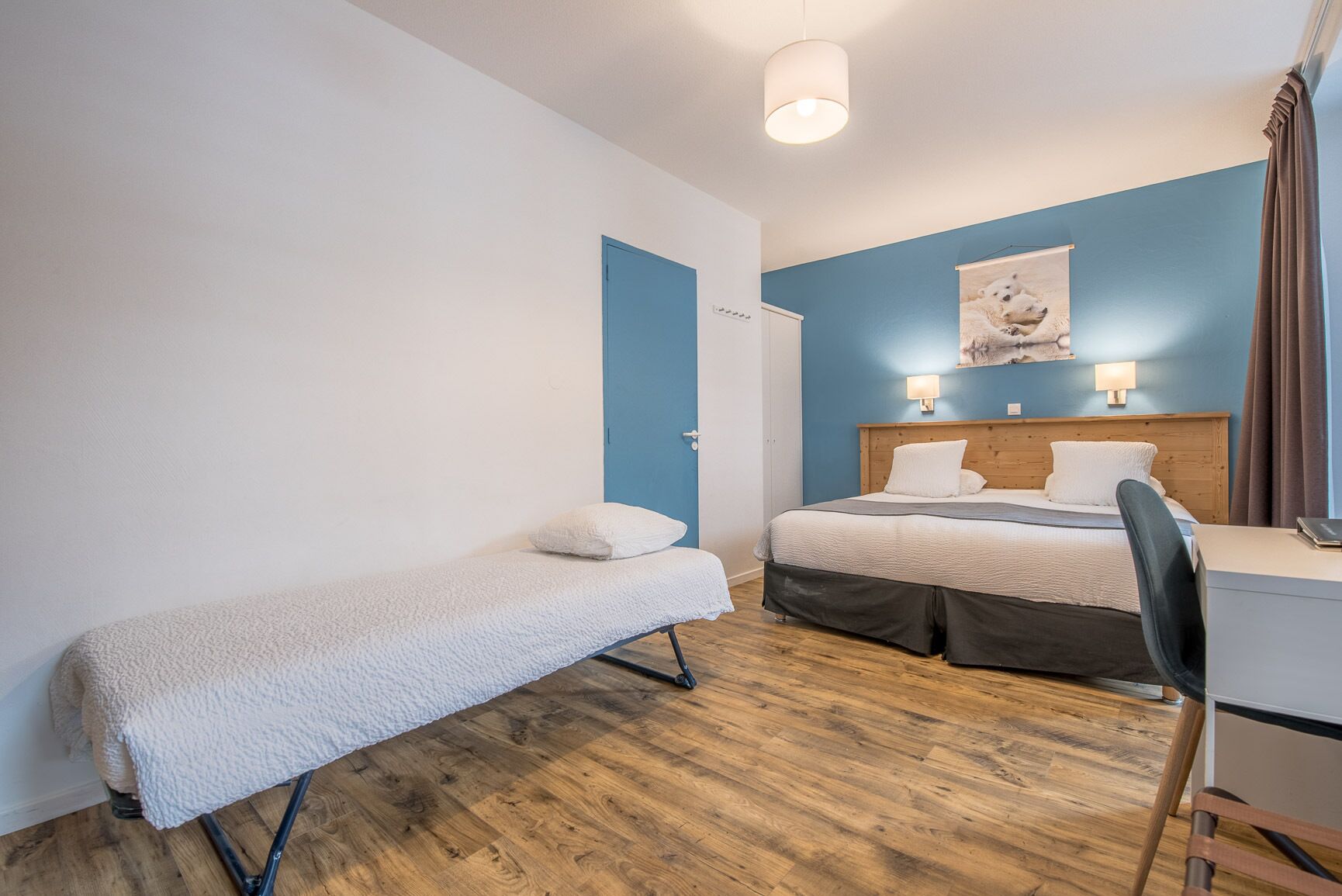 A room with a single bed, a small desk, and a bench.