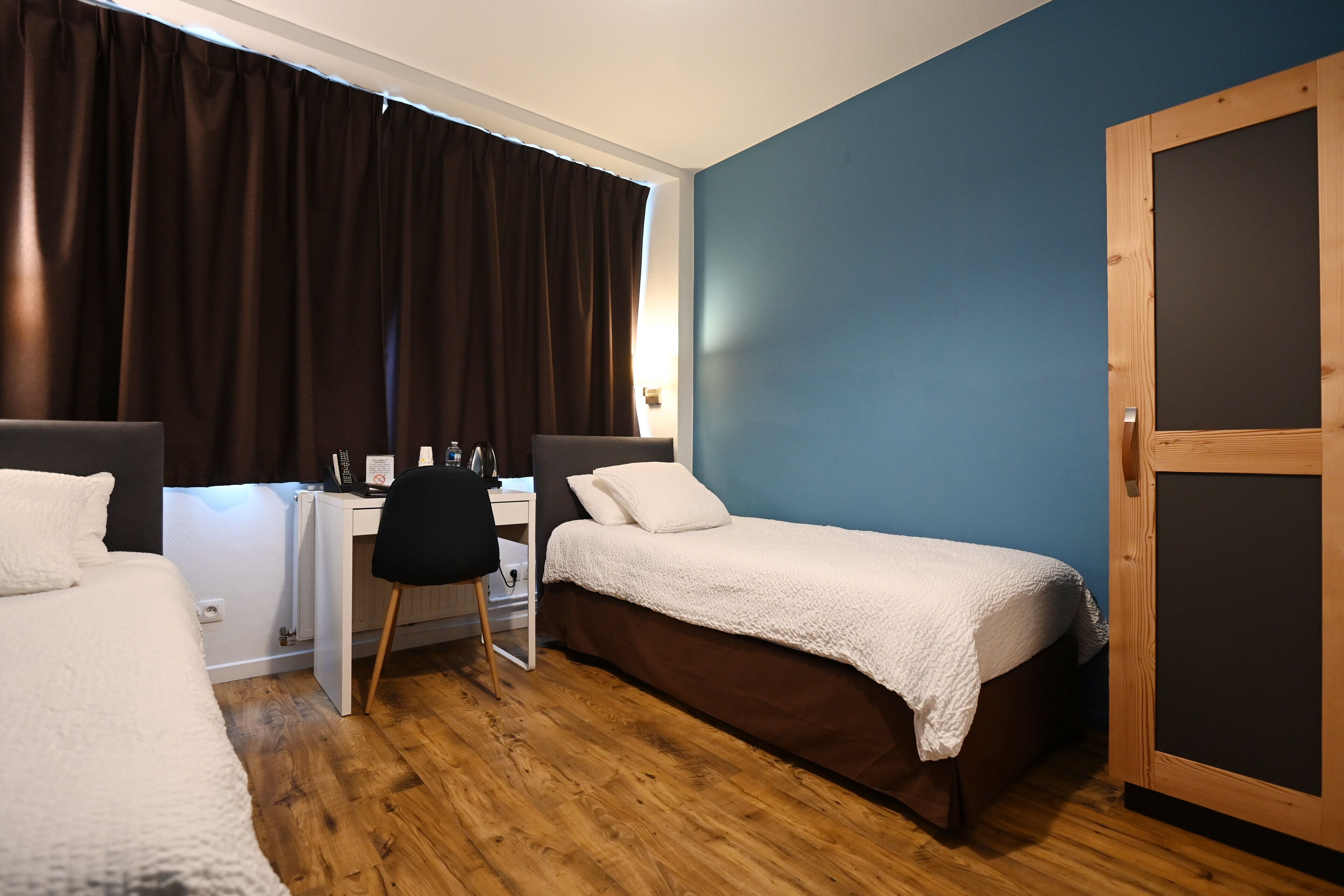 Ein Zimmer mit zwei Betten, einem Schreibtisch und einem Stuhl.