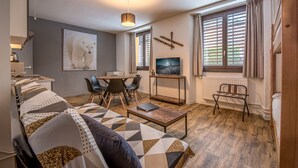 Una sala de estar moderna con un sofá, una mesa de centro, un televisor y un comedor con sillas.