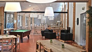 Un espacio interior moderno con paredes de madera, una mesa de billar y sillones de cuero negro.