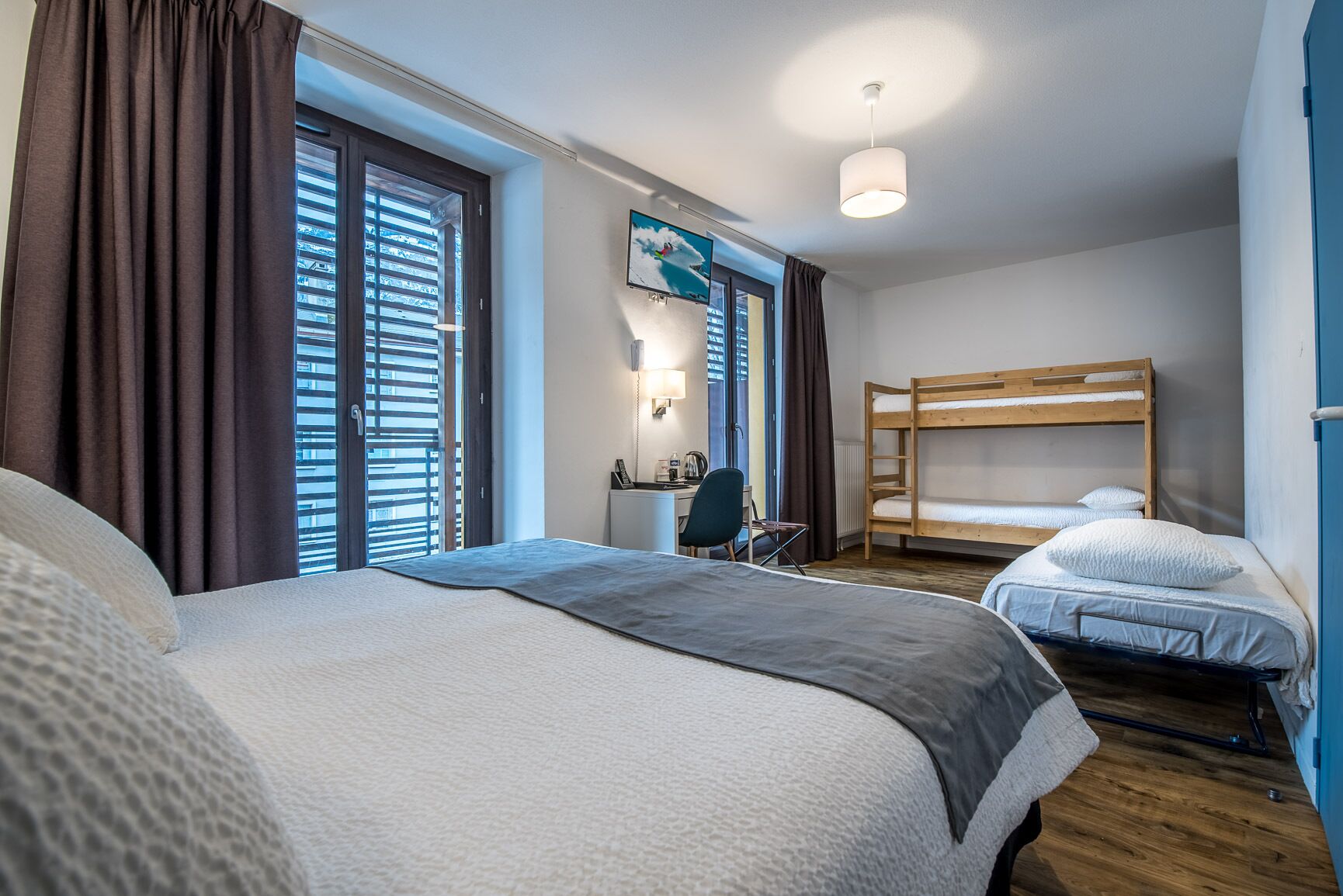 A hotel room with two beds, a desk, and a chair.