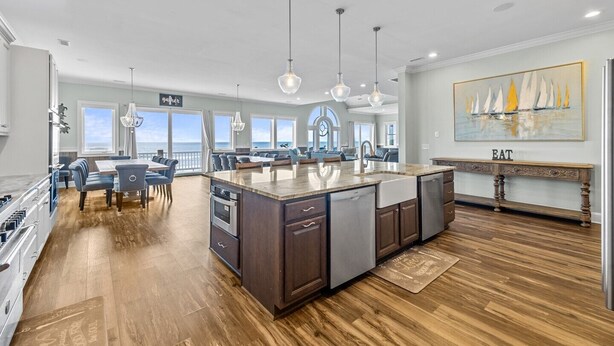 A spacious kitchen with a large island, modern pendant lighting, and a view of the ocean. - Experience oceanfront luxury at Topsail Manor, a spacious 8-bedroom paradise in North Topsail Beach. (North Topsail Beach)