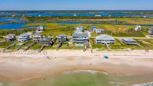 An aerial view of a coastal property with multiple houses, a beach, and a water body. - Experience oceanfront luxury at Topsail Manor, a spacious 8-bedroom paradise in North Topsail Beach. (North Topsail Beach)