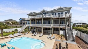 A multi-story building with a pool, outdoor seating, and a staircase leading to the upper levels. - Experience oceanfront luxury at Topsail Manor, a spacious 8-bedroom paradise in North Topsail Beach. (North Topsail Beach)