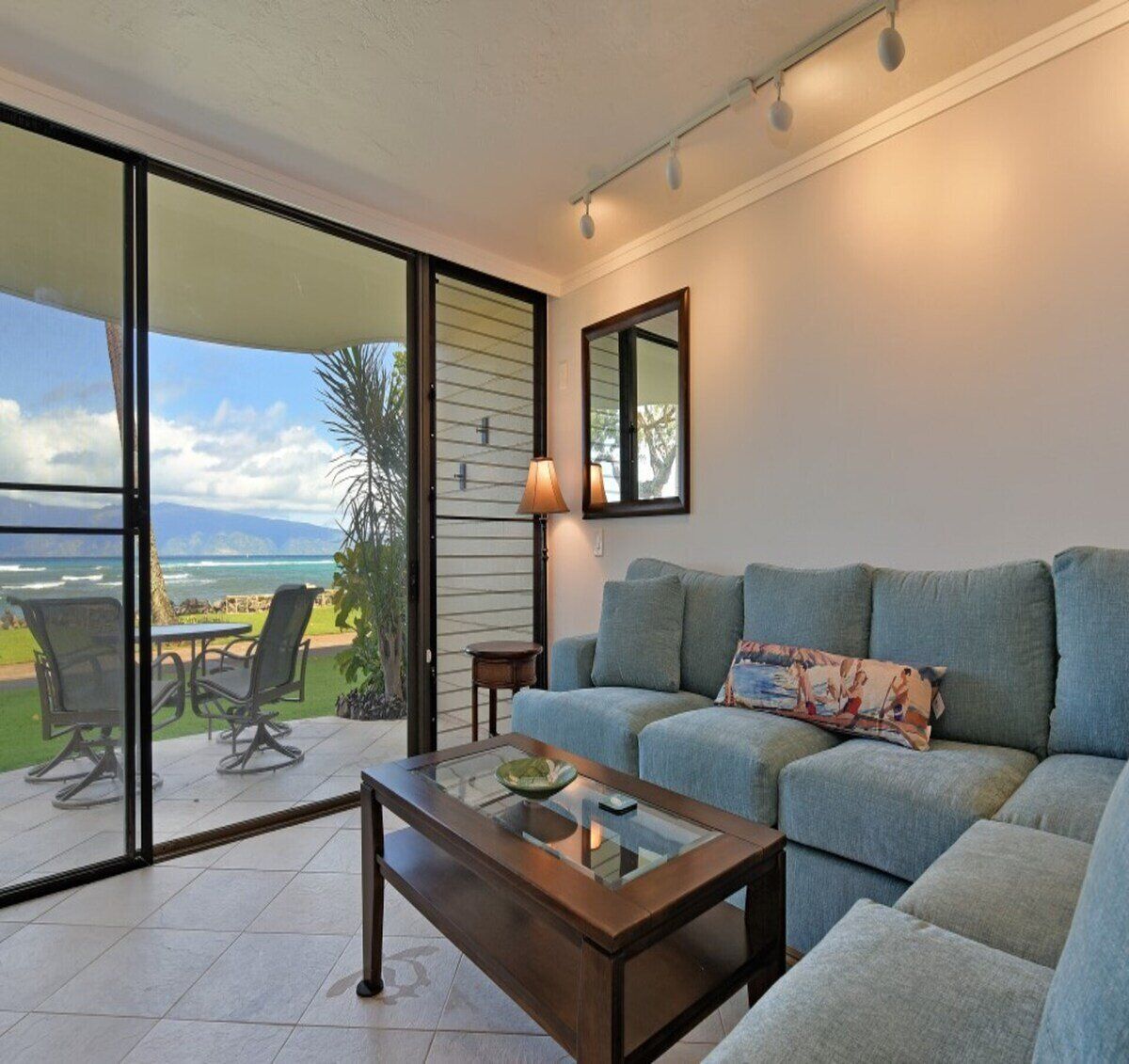 A living room with a glass door leading to a patio, a sofa, a coffee table, and a lamp.