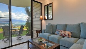Un salon doté d’une porte vitrée donnant sur une terrasse, d’un canapé, d’une table basse et d’une lampe.