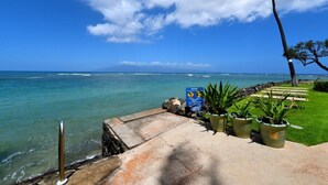 Une promenade en bord de mer offrant une vue dégagée sur l’océan, un panneau indiquant un avertissement et des plantes en pot le long du sentier.