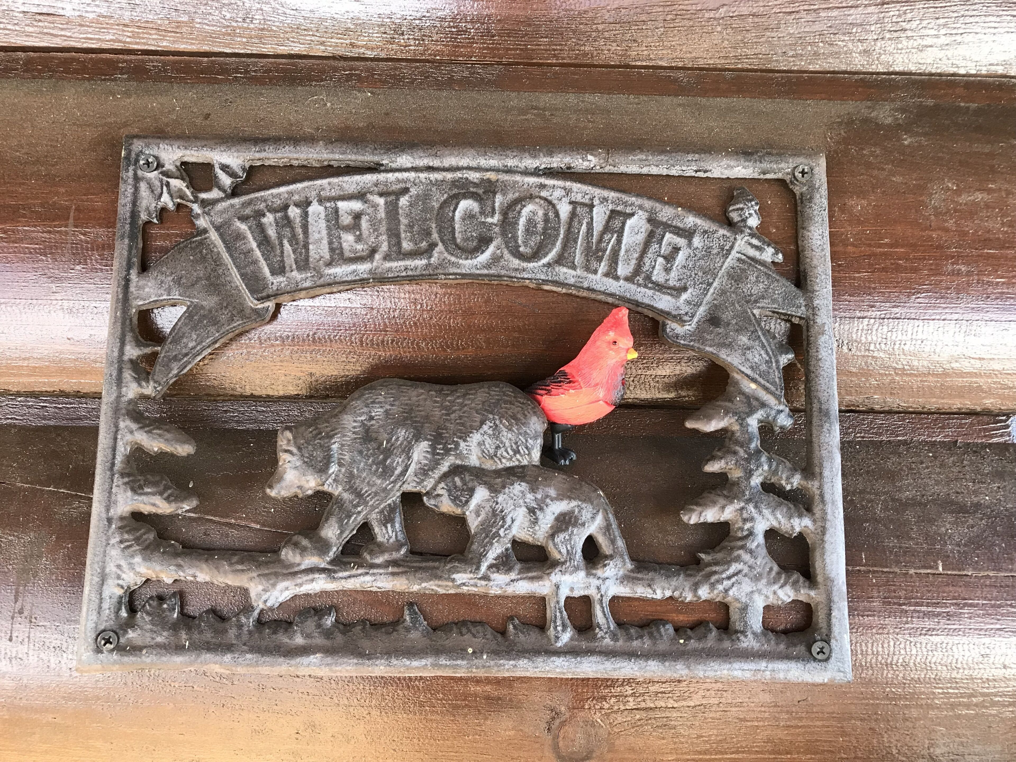 A metal welcome sign with a bird and a deer.