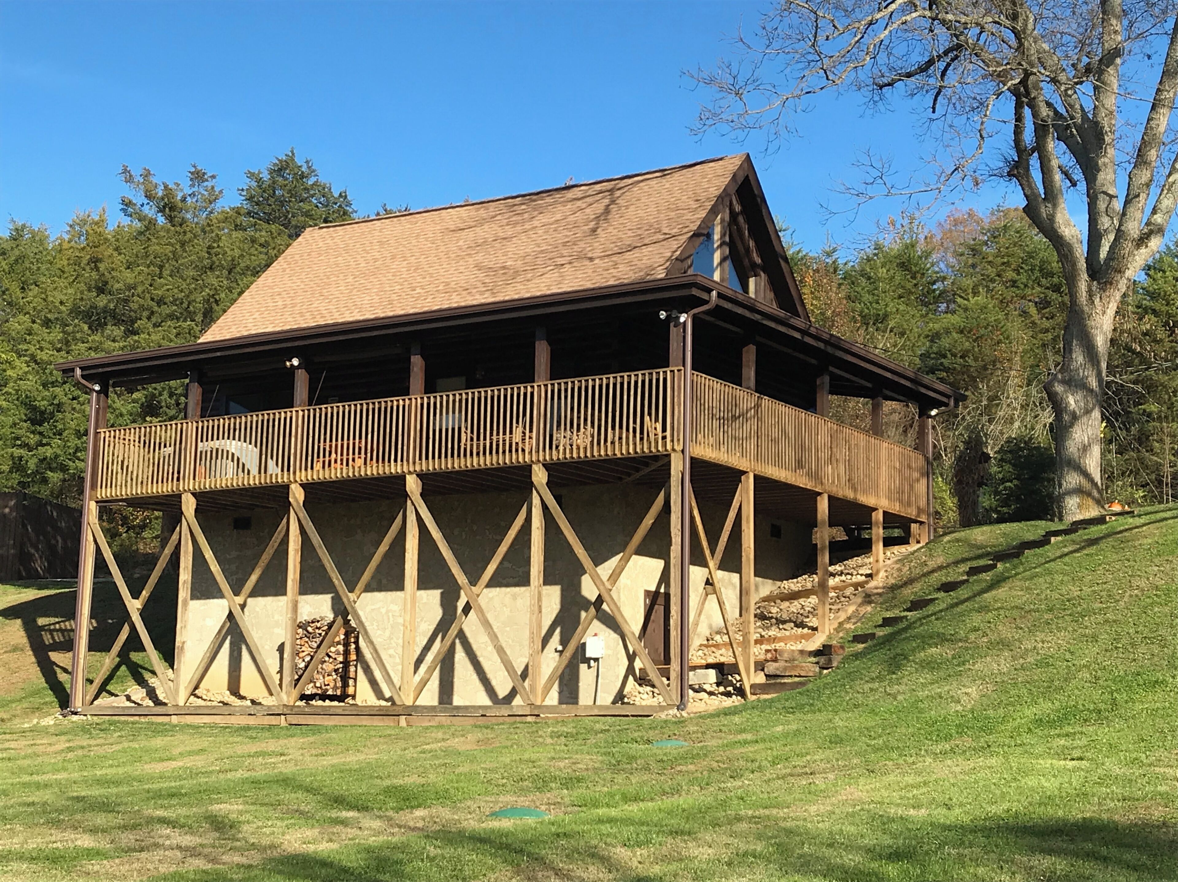 Eine Holzhütte mit Balkon, umgeben von Bäumen und einer Rasenfläche.