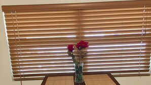 A dining table with a vase of red roses, set against a window with horizontal blinds. - HUGE UPDATED & CLEAN Studio Apartment, Downtown & Beaches Nearby!  (St. Petersburg)
