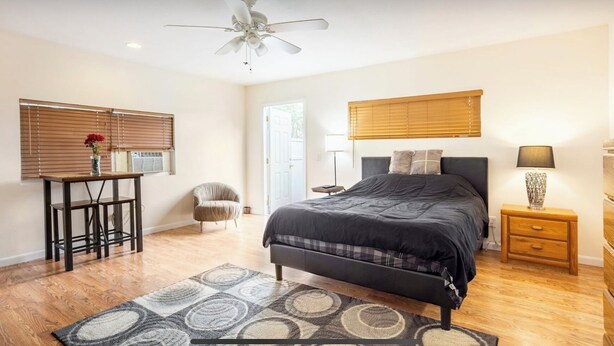 A bedroom with a bed, bedside table, lamp, chair, and a ceiling fan. - HUGE UPDATED & CLEAN Studio Apartment, Downtown & Beaches Nearby!  (St. Petersburg)