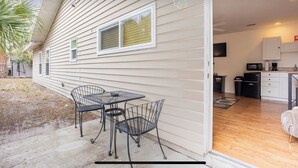 A house with a patio area featuring a table and chairs, a kitchen with appliances, and a view of the backyard. - HUGE UPDATED & CLEAN Studio Apartment, Downtown & Beaches Nearby!  (St. Petersburg)