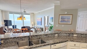 A kitchen with granite countertops, white cabinetry, and a double sink. - Beach Club Corner Unit! Direct Gulf View - Pools - Beach - Grill -Upgraded Cable (Gulf Shores)